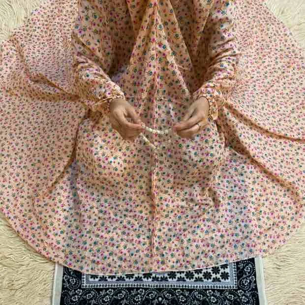 woman wearing namaz chadar with sleeves with hands raised in prayers