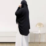 A woman wearing a black makhna hijab, providing full coverage for the head, neck, and shoulders without pins. CLOTHIFYDOTPK