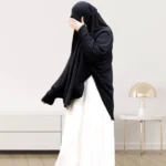 A woman wearing a black makhna hijab, providing full coverage for the head, neck, and shoulders without pins. CLOTHIFYDOTPK