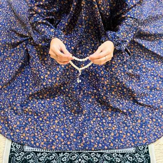 A women peacefully performing salah wearing printed namaz chadar.