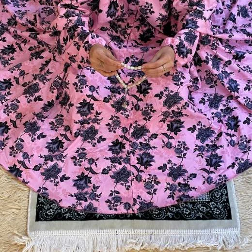 A woman using a Winter Namaz Chadar, performing namaz. Clothifydotpk