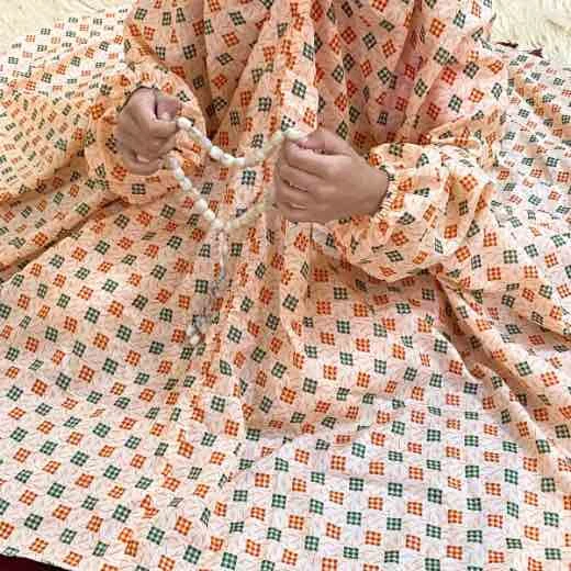 kid wearing namaz chadar with sleeves with hands raised in prayers