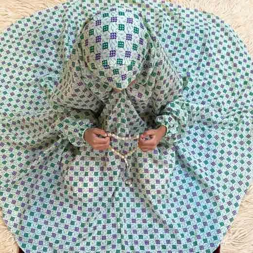 kid wearing namaz chadar with sleeves with hands raised in prayers