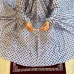 A women peacefully performing salah wearing printed namaz chadar.