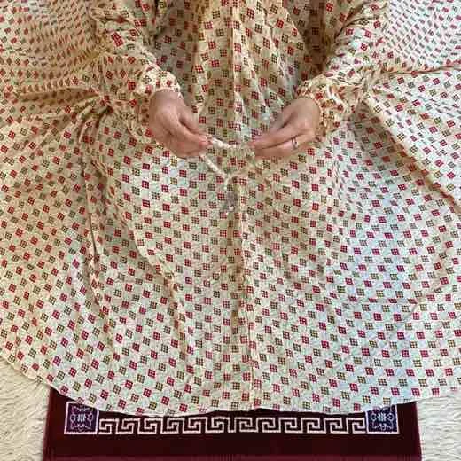 A women peacefully performing salah wearing printed namaz chadar.