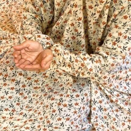 A woman using a breathable soft swiss lawn Namaz Chadar with Sleeves, performing salah By Clothifydotpk