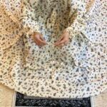 A woman using a breathable soft swiss lawn Namaz Chadar with Sleeves and pocket, performing salah By Clothifydotpk
