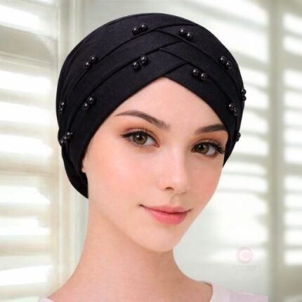 A woman wearing a tie-back fancy 3 layer pearl hijab cap with delicate pearls, visible under a sheer or light hijab.