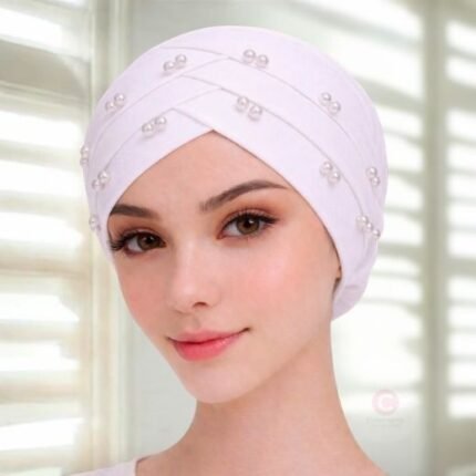 A woman wearing a tie-back fancy 3 layer pearl hijab cap with delicate pearls, visible under a sheer or light hijab.