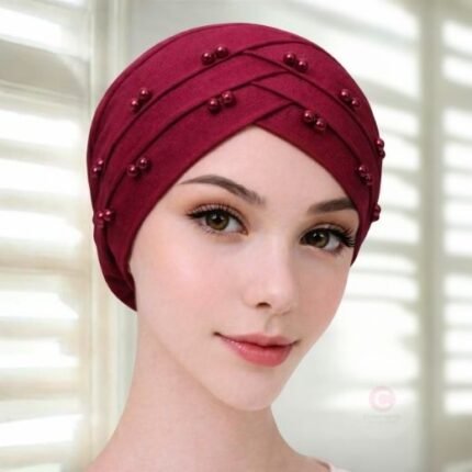 A woman wearing a tie-back fancy 3 layer pearl hijab cap with delicate pearls, visible under a sheer or light hijab.