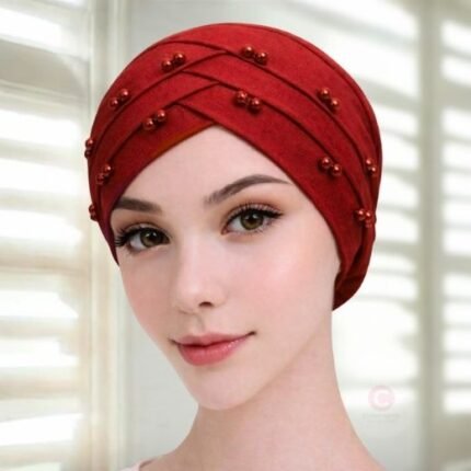 A woman wearing a tie-back fancy 3 layer pearl hijab cap with delicate pearls, visible under a sheer or light hijab.