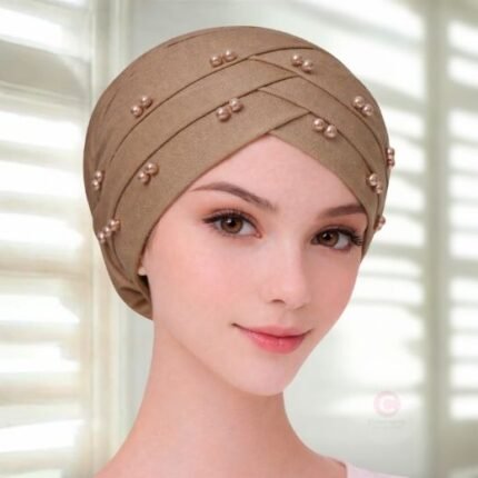 A woman wearing a tie-back fancy 3 layer pearl hijab cap with delicate pearls, visible under a sheer or light hijab.