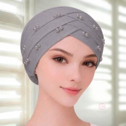 A woman wearing a tie-back fancy 3 layer pearl hijab cap with delicate pearls, visible under a sheer or light hijab.
