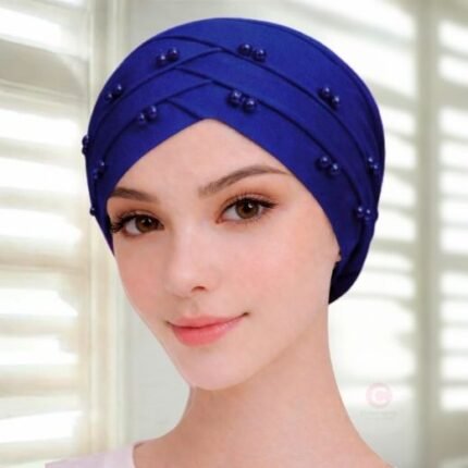 A woman wearing a tie-back fancy 3 layer pearl hijab cap with delicate pearls, visible under a sheer or light hijab.