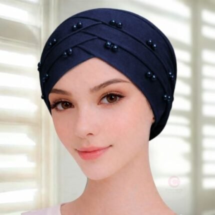 A woman wearing a tie-back fancy 3 layer pearl hijab cap with delicate pearls, visible under a sheer or light hijab.