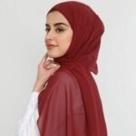 A woman wearing a maroon color ready-to-wear instant chiffon hijab, featuring a soft, flowy drape and pre-stitched design for easy wear with inner under cap. By Clothifydotpk