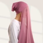 A woman wearing a tea pink color ready-to-wear instant chiffon hijab, featuring a soft, flowy drape and pre-stitched design for easy wear with inner under cap. By Clothifydotpk