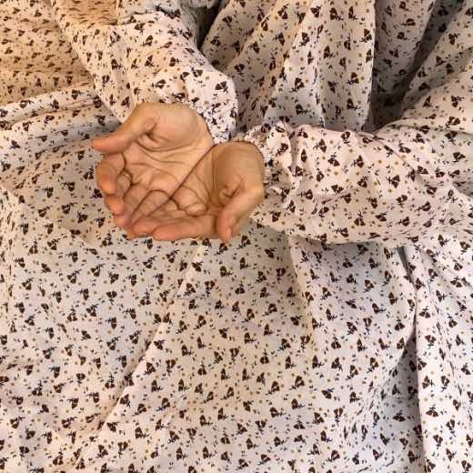 A woman performing Salah comfortably in a breathable, soft Swiss lawn Namaz Chadar with sleeves- available at CLOTHIFYDOTPK