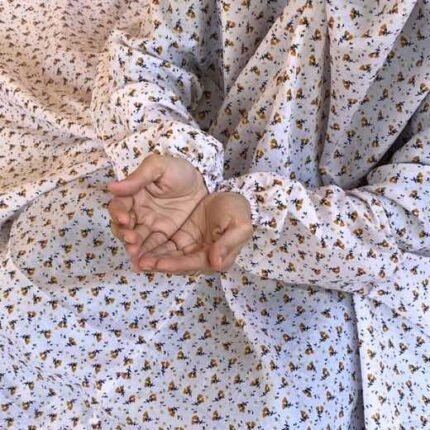 A woman using a breathable soft swiss lawn Namaz Chadar with Sleeves, performing salah By Clothifydotpk