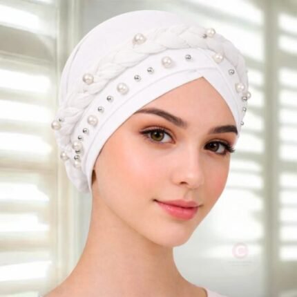 A woman wearing a fancy pearl turban hijab cap with delicate pearls, visible under a sheer or light hijab.