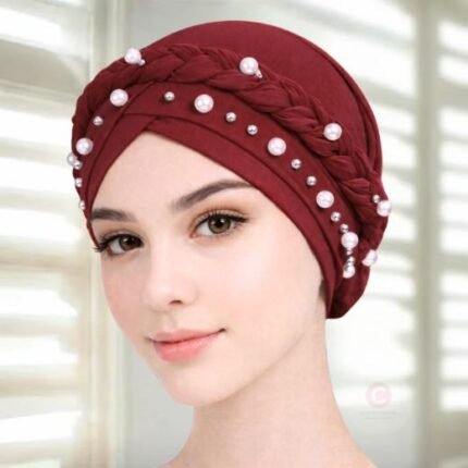 A woman wearing a fancy pearl turban hijab cap with delicate pearls, visible under a sheer or light hijab.