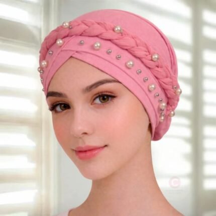 A woman wearing a fancy pearl turban hijab cap with delicate pearls, visible under a sheer or light hijab.