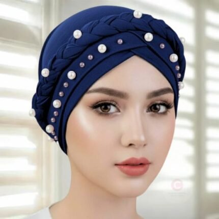 A woman wearing a fancy pearl turban hijab cap with delicate pearls, visible under a sheer or light hijab.