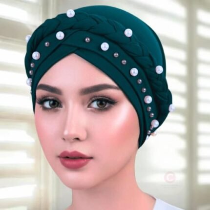A woman wearing a fancy pearl turban hijab cap with delicate pearls, visible under a sheer or light hijab.