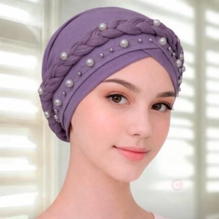 A woman wearing a fancy pearl turban hijab cap with delicate pearls, visible under a sheer or light hijab.