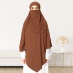 A woman wearing a long, single layer khimar that drapes over the head, and shoulders, falling to about waist length.