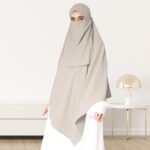 A woman wearing a long, single layer khimar that drapes over the head, and shoulders, falling to about waist length.