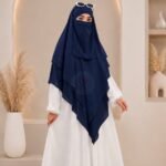 A woman wearing a three layer khimar, with the first layer covering her head and draping down over her chest, and two additional sheer or lightweight layers cascading underneath. BY CLOTHIFYDOTPK