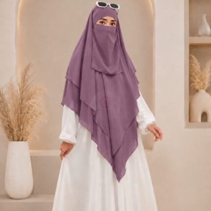 A woman wearing a three layer khimar hijab, with the first layer covering her head and draping down over her chest, and two additional sheer or lightweight layers cascading underneath. BY CLOTHIFYDOTPK
