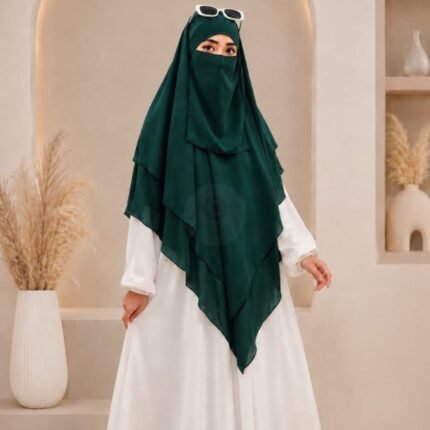 A woman wearing a three layer khimar hijab, with the first layer covering her head and draping down over her chest, and two additional sheer or lightweight layers cascading underneath. BY CLOTHIFYDOTPK