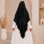 A woman wearing a three layer khimar, with the first layer covering her head and draping down over her chest, and two additional sheer or lightweight layers cascading underneath. BY CLOTHIFYDOTPK