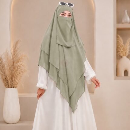 A woman wearing a white 3 layer khimar hijab, with the first layer covering her head and draping down over her chest, and two additional sheer or lightweight layers cascading underneath. BY CLOTHIFYDOTPK