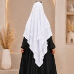 A woman wearing a white three layer khimar hijab, with the first layer covering her head and draping down over her chest, and two additional sheer or lightweight layers cascading underneath. BY CLOTHIFYDOTPK