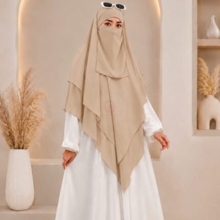 A woman wearing a three layer khimar hijab, with the first layer covering her head and draping down over her chest, and two additional sheer or lightweight layers cascading underneath. BY CLOTHIFYDOTPK