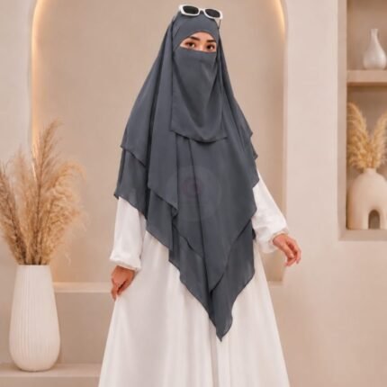 A woman wearing a three layer khimar hijab, with the first layer covering her head and draping down over her chest, and two additional sheer or lightweight layers cascading underneath. BY CLOTHIFYDOTPK