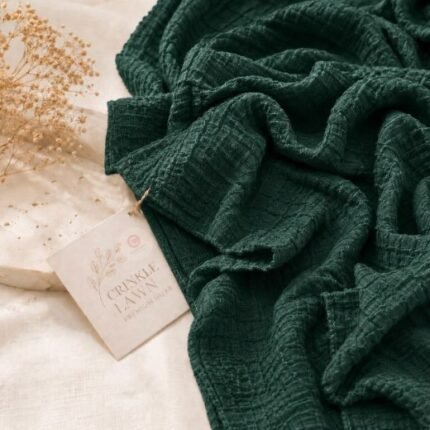 Close-up of emerald green crinkle lawn hijab fabric showing fine permanent pleats and lightweight weave. BY CLOTHIFYDOTPK