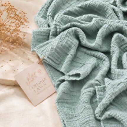 Close-up of sage green crinkle lawn hijab fabric showing fine permanent pleats and lightweight weave. BY CLOTHIFYDOTPK