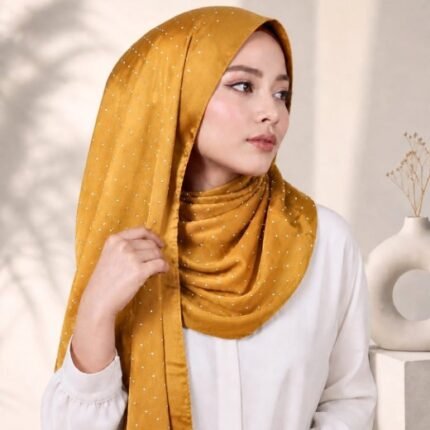 Woman wearing an elegant stone silk hijab in a sun gold color – soft fabric draping over her head and shoulder with natural lighting.