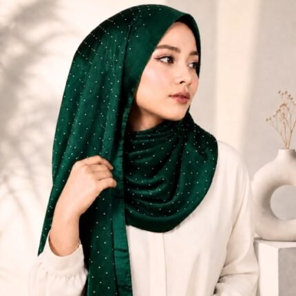 Woman wearing an elegant stone silk hijab in a emerald color – soft fabric draping over her head and shoulder with natural lighting.