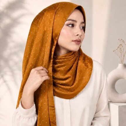 Woman wearing an elegant stone silk hijab in a amber color – soft fabric draping over her head and shoulder with natural lighting.