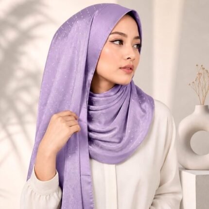 Woman wearing an elegant stone silk hijab in a lavender color – soft fabric draping over her head and shoulder with natural lighting.