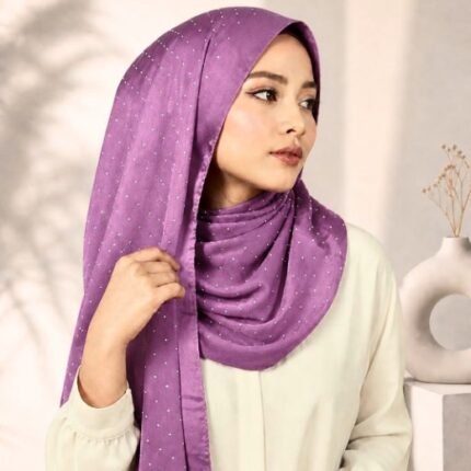 Woman wearing an elegant stone silk hijab in a mauve color – soft fabric draping over her head and shoulder with natural lighting.