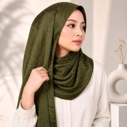 Woman wearing an elegant stone silk hijab in a olive color – soft fabric draping over her head and shoulder with natural lighting.