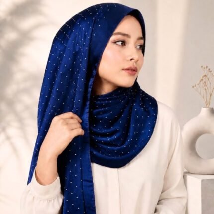 Woman wearing an elegant stone silk hijab in a twilight blue color – soft fabric draping over her head and shoulder with natural lighting.