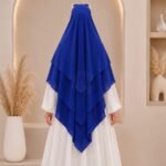 A woman wearing a three layer khimar, with the first layer covering her head and draping down over her chest, and two additional sheer or lightweight layers cascading underneath. BY CLOTHIFYDOTPK