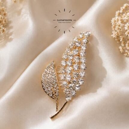 A close-up of a modern, sophisticated brooch featuring a brilliant arrangement of clear rhinestones that catch the light. By Clothifydotpk